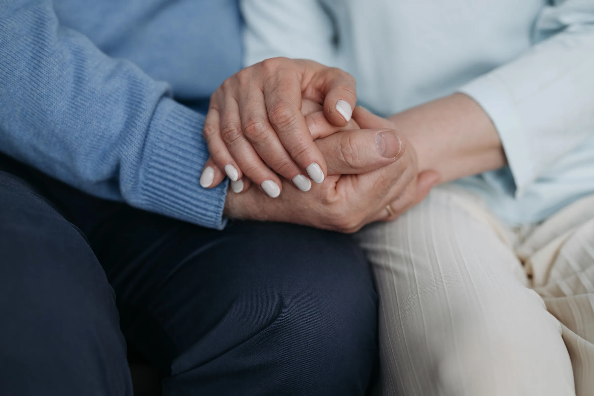 An older couple sitting close together and holding hands